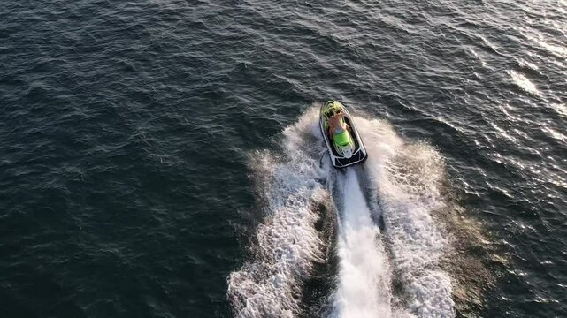 Woman rides a jet ski across the sea at sunset. Fast, free, and full of tropical energy in golden evening light.