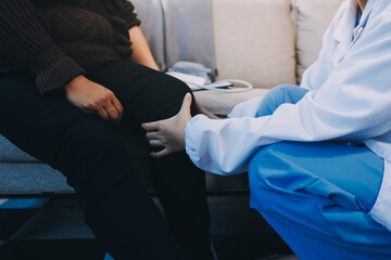 Young doctor examines senior patient's leg.