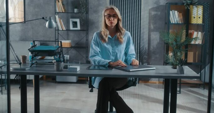Exhausted female business worker in office at desk closing laptop after work and taking lotus pose, meditating and relaxing at workplace. A businesswoman in the company takes a break meditating.