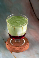 A layered strawberry matcha latte in a glass, showcasing the vibrant red strawberry base and the green matcha top