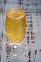 A close-up of golden beer in stemmed glass with numerous small bubbles rising to the surface on a textured background. Concept of celebration and indulgence