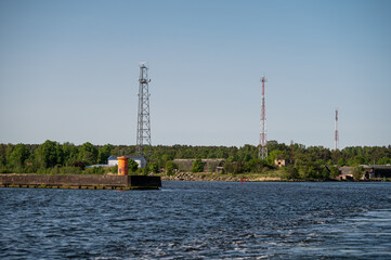 Waterfront view showcasing communication towers and lush greenery on a sunny day