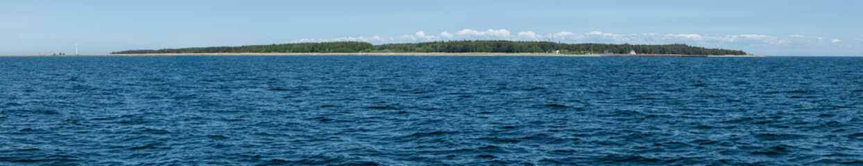 View of a peaceful coastline with lush greenery and calm blue waters on a sunny day