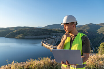 Engineer inspecting dam with laptop for workplace safety