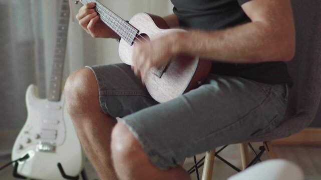 4K close up Ukulele or uke string instrument video popular on Hawaii islands. Man playing nylon strings during music lessons. Musical education and art people concept footage.