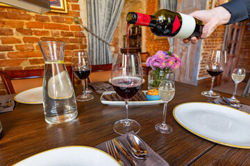 Hand Pouring Red Wine into a Glass at a
