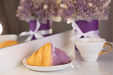 Cup of tea and berry croissant, bouquet of violet flowers