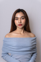 Portrait of gorgeous elegant sensual blonde Asian woman wearing fashionable light blue off-shoulder top looking at camera isolated on white background. Beauty, lifestyle and fashion concept.