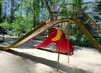 playground in the park. slides for children in the courtyard of the house.
view of the playground with two slides, one of them is high metal, the other is smaller in the form of a red elephant for sma