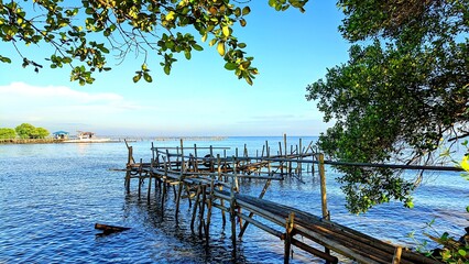 Scenic view of calm blue sea with bamboo bridge under shady tree at Alar Beach, Tangerang, Indonesia