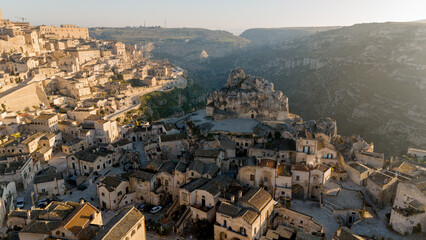 Drone view of Materas iconic rock-hewn church, Chiesa di Santa Maria di Idris, glowing in soft morning light. A hauntingly beautiful symbol of the citys ancient heritage.