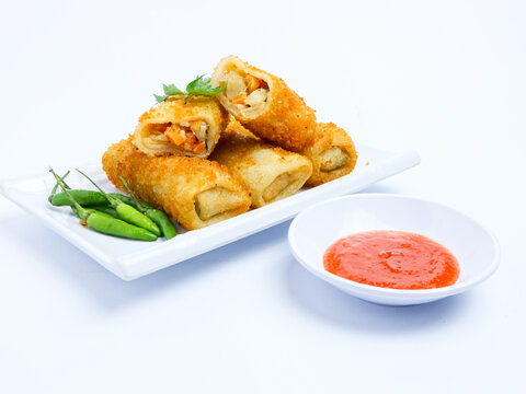 Indonesian risoles filled with vegetables, served with fresh green chilies on a white plate. Crispy breadcrumb coating on white background