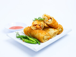 Indonesian risoles filled with vegetables, served with fresh green chilies on a white plate. Crispy breadcrumb coating on white background