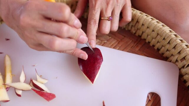 A chef is carving an apple into Thai patterns with a stencil knife.