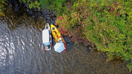 Two kayaks near small island in the middle of the lake view in aerial shot. Beautiful island in Canada. Aquatic sports in a kayak at the lake during summer
