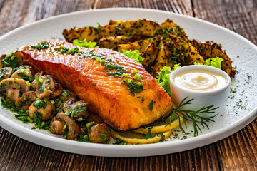 Seared salmon steak with champignons, mayonnaise and baked potatoes on wooden table	