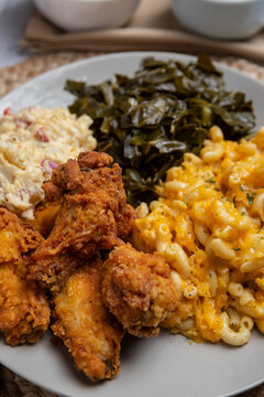 Home cooked meal plate of southern cooked food including collard greens, potato salad, fried chicken and macaroni and cheese