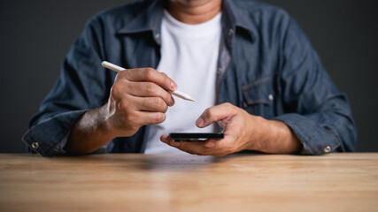 Person Using Smartphone with Stylus on Wooden Table in Minimalist Setting, Close-Up Capture of Hands Engaged in Digital Interaction and Creative Process