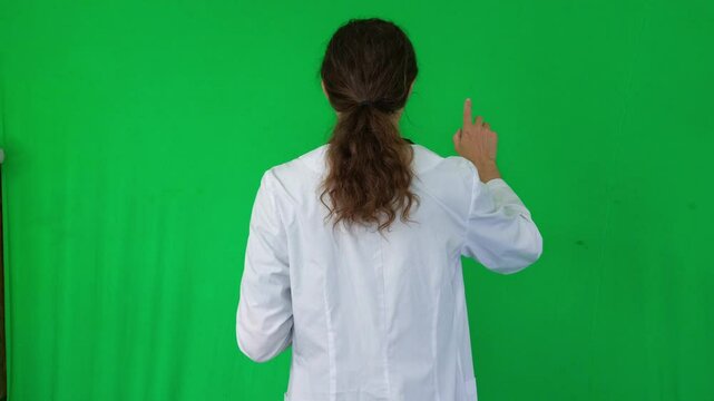 A mid-shot captures a studious and professional mood as a person in a white lab coat meticulously uses a digital tablet, suggesting research, diagnosis, or data entry, green screen background