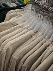 Fototapeta premium Beige sweatshirts neatly arranged on hangers in a clothing store during daylight hours