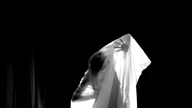 Young dancer performing under white veil in black and white. Selective focus