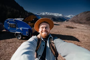 Selbstklebende Fototapeten Young happy man hipster traveler making selfie background camper car on mountain. Concept one life adventure trip, vacation. © Parilov