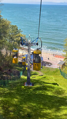 Bright yellow funicular cabins move along a track toward the seashore, offering a scenic coastal...