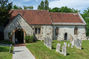 Fototapeta premium Brockenhurst, UK - May 31st 2025: Headstones in the graveyard in front of St Nicholas’ Church. 