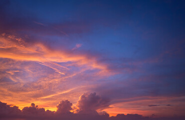 Bright sunset with setting sun behind vivid orange and yellow clouds