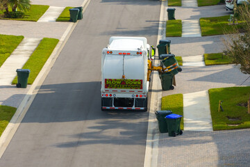 Garbage removal in residential area. Waste truck loading household rubbish while driving on...