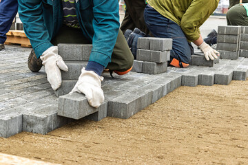 Construction workers laying pavers on a new outdoor pathway during a sunny afternoon