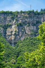 Vertical view of a waterfall cascading down a rocky cliff near Trento, Italy