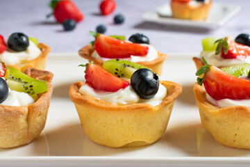 Tartaletas de crema de queso y fruta fresca en bandeja de cerámica blanca