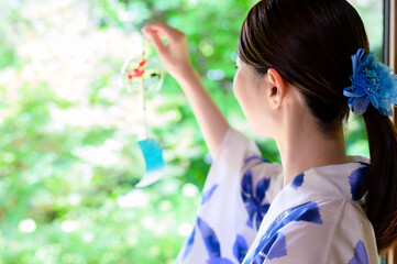 風鈴を手に夏の涼しさを感じる浴衣姿の女性の静かな時間
