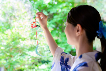 夏の風鈴を見つめる浴衣姿の女性の後ろ姿が映す静かな時間