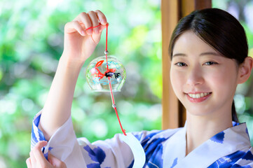 風鈴を手に笑顔を見せる浴衣姿の女性の夏の涼やかさ