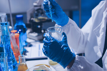 Scientist pipetting medical samples into microplate in laboratory