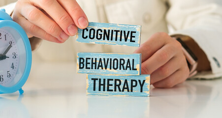 A person is holding a blue block with the word Cognitive Behavioral Therapy