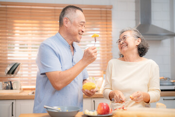 Joyful elderly couple cooking together in modern kitchen during sunny day