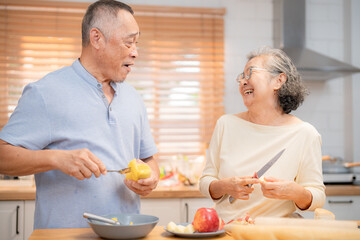 Elderly couple enjoys cooking together in kitchen while preparing healthy meals with fresh ingredients