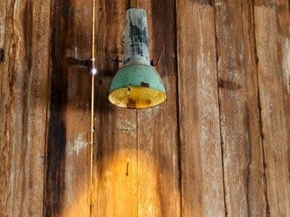 A weathered, vintage style hanging lamp mounted on a natural wooden plank wall