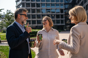 Diverse business people enjoying coffee break and chatting outdoors in corporate business district