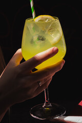 Close-up of a hand holding a glass of bright yellow limoncello cocktail. Traditional Southern...