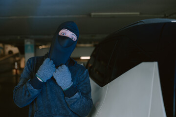 Mysterious figure in a parking garage wearing a mask, preparing for an uncertain activity at night