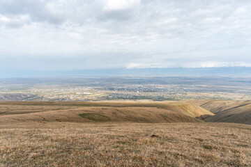 Distant view of Kyrgyz tourist town Karakol under cloudy sky. in October.