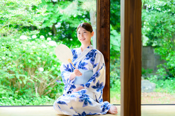 庭の緑を眺めながら微笑む浴衣姿の女性が持つ穏やかな夏の時間