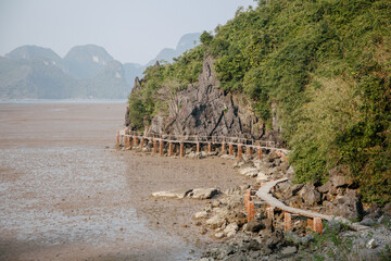 Low tide on the beach at sunset, wooden bridge in mountains, Ha long bay, Vietnam