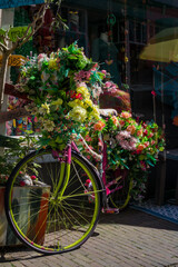 Old vintage woman bicycle decorated with pink flowers on small bridge in old part of Deventer. High quality photo
