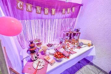 Candy bar pink wedding decorated standing of festive table with deserts, strawberry tartlet and cupcakes