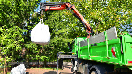 Crane with a big bag of stones. It is a white big bag with decorative stones for the property.